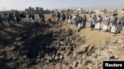 People gather around a crater cause by an airstrike in Amran province, northwest of Yemen's capital, Sana'a, April 12, 2015. 