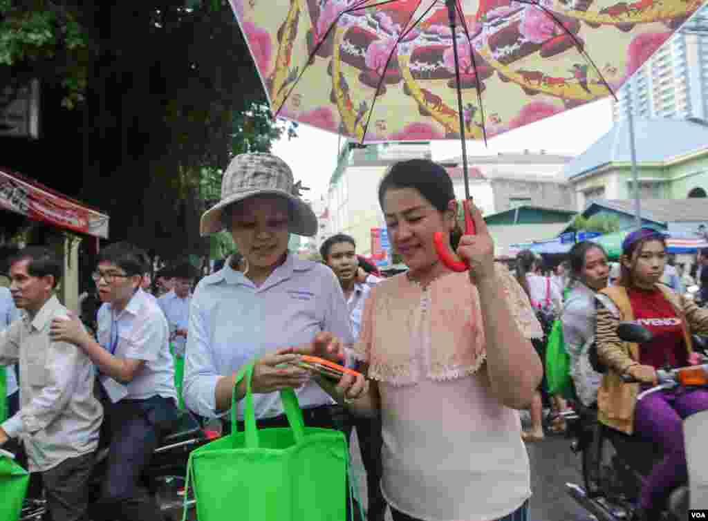 ម្ដាយ​បាំង​ឆ័ត្រ​ឲ្យ​កូនស្រី​ដែលទើប​តែ​ចេញពី​បន្ទប់​ប្រឡង​នៅ​ថ្ងៃ​បញ្ចប់​​នៅ​វិទ្យាល័យ​ព្រះ​យុគន្ធ នៅ​ថ្ងៃ​អង្គារ ទី​២៣ ខែសីហា ឆ្នាំ​២០១៦ នៅ​រាជធានី​ភ្នំពេញ។ ​(ឡេង ឡែន/VOA)