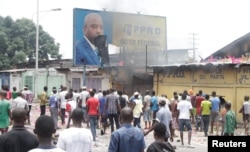 FILE - Congolese opposition supporters chant slogans as they deface a billboard of President Joseph Kabila during a march to press him to step down in the Democratic Republic of Congo's capital Kinshasa, Sept. 19, 2016.