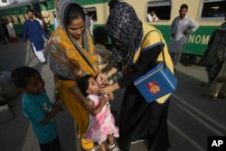A Pakistani health worker gives a polio vaccine to a girl at Karachi railway station in Pakistan, April 11, 2018.