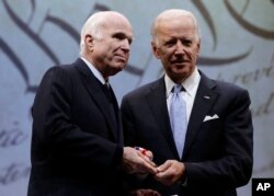FILE - Sen. John McCain, R-Ariz., receives the Liberty Medal from former Vice President Joe Biden, chairman of the National Constitution Center's Board of Trustees, in Philadelphia, Oct. 16, 2017.