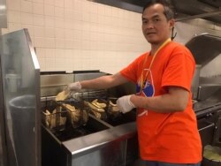 Satriyo Utomo alias Nanang, ketua tim relawan dapur Muktamar IMSA 2019, menggoreng ikan filet di dapur (VOA/Karlina).