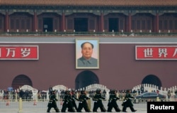 FILE - Paramilitary policemen march at the Tiananmen Sqaure before the fourth plenary meeting of the National People's Congress (NPC) at the Great Hall of the People in Beijing, March 14, 2013.