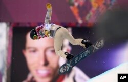 Shaun White of the U.S. performs a jump near a picture of himself during the men's snowboard halfpipe qualification round at the 2014 Sochi Winter Olympic Games in Rosa Khutor February 11, 2014. REUTERS/Dylan Martinez (RUSSIA - Tags: SPORT SNOWBOARDING O