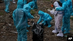 រូបឯកសារ៖ ស្ត្រី​ម្នាក់​ដែល​ពាក់​ឧបករណ៍​និង​ឯកសណ្ឋាន​ការពារ​ពណ៌ស មើល​សាកសព​ស្វាមី​របស់​អ្នកស្រី ដែល​បាន​ស្លាប់​ដោយសារ​ជំងឺកូវីដ១៩ នៅ​ប្រទេស​ឥណ្ឌា កាលពី​ថ្ងៃ១០ ខែកញ្ញា ឆ្នាំ២០២០។