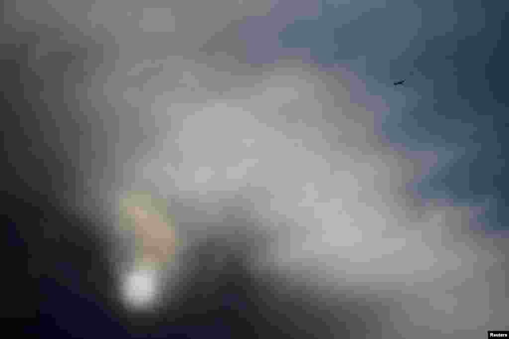 A passenger jet navigates past storm clouds as it prepares to land at Los Angeles International Airport amid the beginning of a major wind storm in Southern California, taken from the city of Commerce, California.