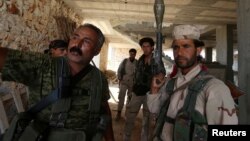 Fighters of the Syria Democratic Forces (SDF) stand inside a building near Manbij, in Aleppo Governorate, Syria on June 17, 2016. 