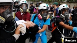 Voluntarios de la Cruz Verde atienen a una mujer herida durante la marcha contra el hambre en Caracas.