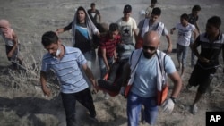 Petugas medis dan pengunjuk rasa Palestina mengevakuasi seorang pria yang terluka dalam bentrokan dengan tentara Israel di Gaza, 21 Juli 2017.