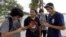 FILE -- Brian Vega, left, Peyton Ruiz, second from left, and Max Marrero, right, check their smartphones at Bayfront Park in downtown Miami, Florida.