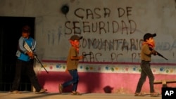 FILE - Children train with fake weapons during a display for the media designed to to attract the federal government's attention to the dangers of organized crime in Ayahualtempa, Guerrero state, Mexico, Wednesday, April 28, 2021. (AP Photo/Marco Ugarte)