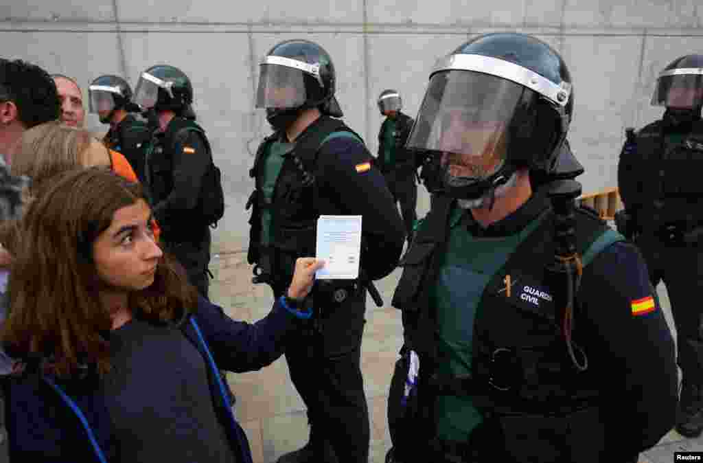 A woman shows a ballot to a Spanish Civil Guard officer outside a polling station for the banned independence referendum in Sant Julia de Ramis, Oct. 1, 2017.