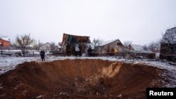 Lokalna stanovnica stoji pored kratera izazvanog udarom ruske rakete u Kijevu, Ukrajina, 11. decembra 2023.