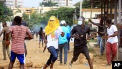 Demonstrators opposed to Ivory Coast President Alassane Ouattara running for a third term confront riot police in Abidjan, Aug. 13, 2020. 