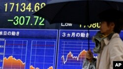 People walk past an electronic board showing the Nikkei stock index in Tokyo, Nov. 2, 2016.
