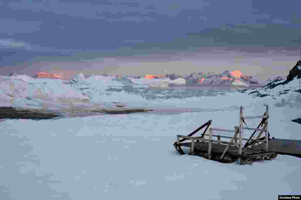 The late summer sun sets over mountains and icebergs around Adelaide Island, Antarctic Peninsula, as twenty-four hour daylight gives way to the long polar night of winter. (Image courtesy of Hamish Pritchard, British Antarctic Survey)