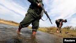 A soldier from the Kachin Independence Army (KIA) puts on his shoes as he and his comrade cross a stream towards the front line in Laiza, Kachin state, January 29, 2013.