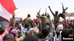 Sudanese military officers and demonstrators ride atop a military tanker as they protest against the army's announcement that President Omar al-Bashir would be replaced by a military-led transitional council, near Defense Ministry in Khartoum, Sudan, April 12, 2019.