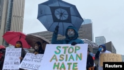 FILE - People hold placards as they gather to protest anti-Asian hate crimes, racism and vandalism, outside City Hall in Toronto, Ontario, Canada, March 28, 2021.