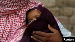 Two-year-old HIV positive boy sits on the lap of his father, in Ratodero, Pakistan, May 24, 2019.