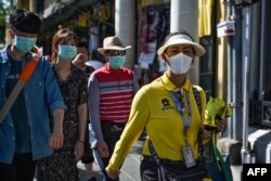 A Thai tour guide (R) escorts Chinese tourists wearing face masks near the Grand Palace in Bangkok on January 27, 2020. - Thailand has detected eight Coronavirus cases so far -- three of whom are receiving treatment in hospital and five of whom have been