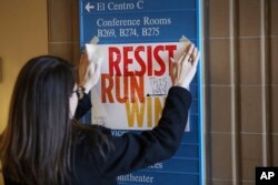 In this Dec. 9, 2017, photo, Lianna Stroster posts a sign directing to a women's candidate training workshop at El Centro College in Dallas. Emily's List, an organization dedicated to electing candidates at all levels of government who support abortion rights, conducted a national recruitment effort, looking to train candidates and potential candidates in numerous states.