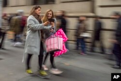 Shoppers carry their purchases as they walk along Fifth Avenue on Black Friday in New York, Friday, Nov. 25, 2016. Stores opened their doors Friday for what is still one of the busiest days of the year, even as the start of the holiday season edges ever earlier and online sales increase.