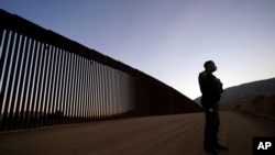 FILE - Border Patrol agent Justin Castrejon speaks in front of newly replaced border wall sections Sept. 24, 2020, near Tecate, Calif.