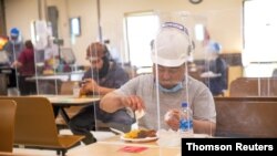  A worker at a hog-processing plant eats behind plexiglass screens installed in the facility's cafeteria to try to contain the spread of COVID-19 within the plant, in Guymon, Oklahoma, U.S., on May 13, 2020. 