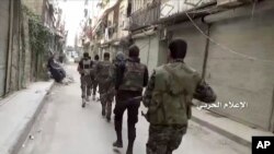  In this still image taken from video provided by the Syrian government-controlled Syrian Central Military Media, government troops patrol inside the Bustan Al-Basha neighborhood of Aleppo, Syria. 