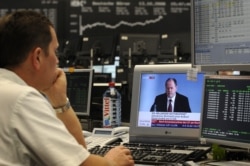 FILE - A share trader watches German Finance Minister Peer Steinbrueck's on an incresing impact of the global financial crisis, on television at the Frankfurt stock exchange, Oct.13, 2008.