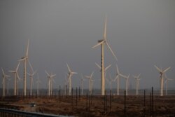 FILE - A car drives near wind turbines on a power station near Yumen, Gansu province, China, September 29, 2020.