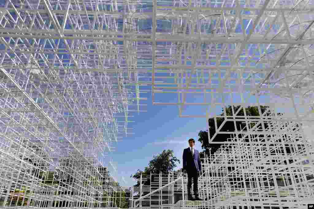 Seorang reporter berdiri di dalam paviliun Serpentine Gallery 2013, yang dirancang oleh arsitek Jepang Sou Fujimoto, di taman Kensington, pusat kota London.