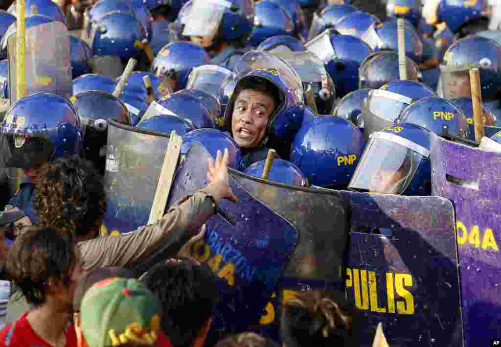 A police officer yells at his colleagues during a clash with protesters when they tried to force their way closer to the gates of the U.S. Embassy in Manila, Philippines, to mark the International Labor Day.
