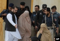 Pakistani officials escort famed Afghan woman Sharbat Gulla in a burqa or veil outside a court in Peshawar, Pakistan, Nov. 4, 2016.