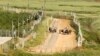 Israeli soldiers stand next to military vehicles along their side of the border with Lebanon, as seen from the southern Lebanese village of Adaisseh, May 4, 2013.