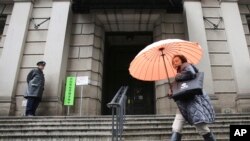 A woman walks past in front of Bank of Japan, Jan. 29, 2016. The Bank of Japan on Friday introduced a negative interest policy for the first time, seeking to shore up a stumbling recovery in the world's third-largest economy. 