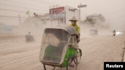 Seorang pengendara becak di Yogyakarta mengenakan masker saat melaju di jalanan yang diselimuti abu vulkanik akibat erupsi gunung Kelud (14/2).