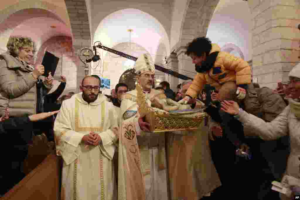 Archbishop Pierbattista Pizzaballa, center, apostolic administrator of the Latin Patriarch of Jerusalem, holds a statue of Baby Jesus in Saint Catherine&#39;s Church at the end of the Christmas Midnight Mass and walks in procession to the &#39;Grotto&#39;, where Christians believe the Virgin Mary gave birth to Jesus Christ, in the adjacent Church of the Nativity in Bethlehem, West Bank, Dec. 25, 2016.