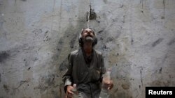Seorang pria berdiri di bawah kucuran air setelah mengisi botol minum dengan air di tengah serangan hawa panas yang melanda Karachi, Pakistan.