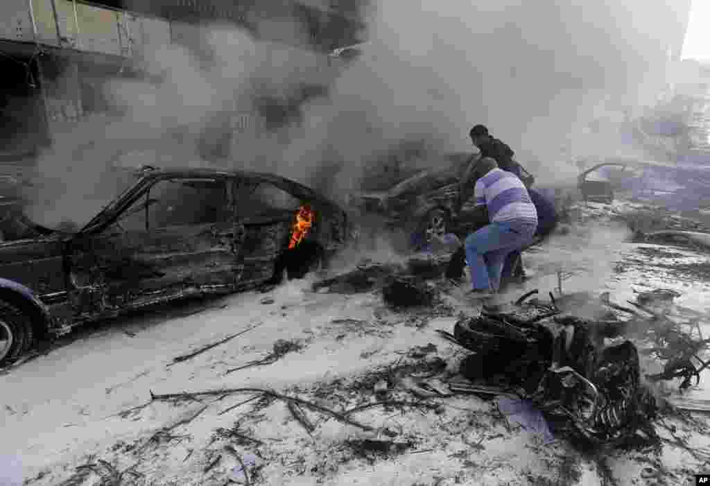 Two men remove a dead body from a burned car, after explosions near the Iranian embassy in Beirut, Nov. 19, 2013. 