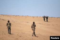 FILE - Men that fled areas of clashes surrender to Syrian Democratic Forces (SDF) fighters north of Raqqa city, Syria, March 8, 2017.