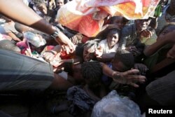 A woman tries to get food at a shelter in the school Liliane Mars Dumarsais Estime after Hurricane Matthew in Les Cayes, Haiti, Oct. 7, 2016.