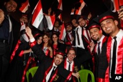 FILE - Baghdad University graduates wave national flags as they celebrate during a graduation ceremony in Baghdad, Iraq, July 14, 2012.