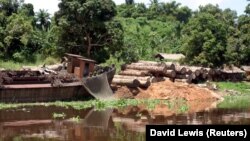 Logs lie next to an old boat on the Congo river October 7, 2004. The world's second largest rainforest stands a greater chance of being protected after the Democratic Republic of Congo's president finally backed a largely ignored ban on new logging. (REUTERS/David Lewis)
