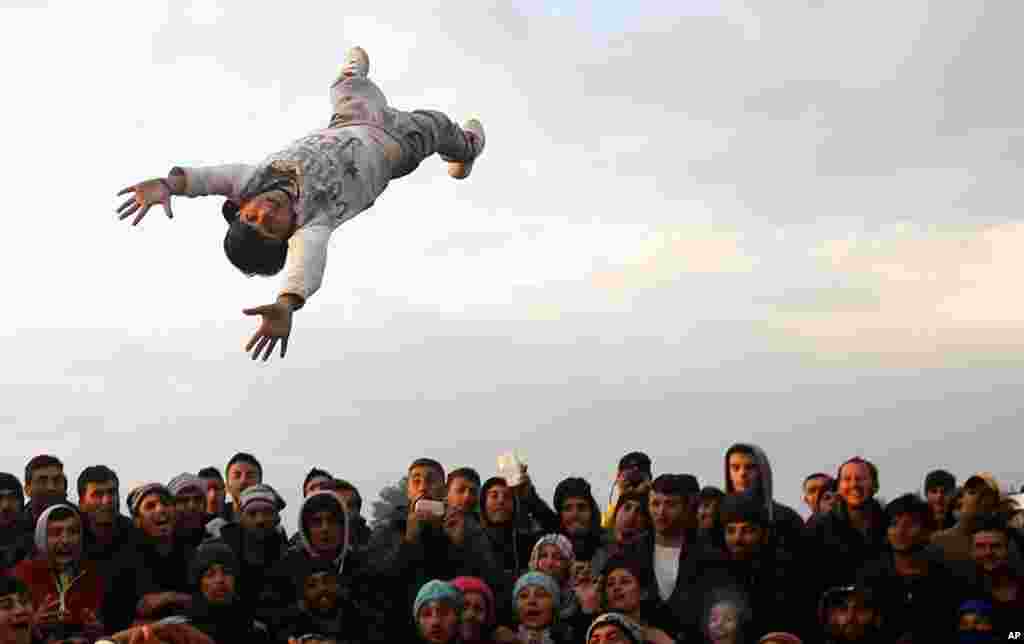 A person is thrown and caught as migrants gather and have a party in the northern Greek border station of Idomeni.&nbsp;