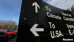 FILE - A sign giving directions is seen in the parking lot of the United States-Canada border in Surrey, British Columbia, Feb. 16, 2017. 