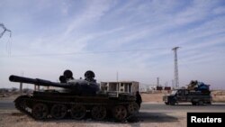 Sebuah mobil bergerak melewati tank yang terabaikan di Aleppo, Suriah, pada 11 Desember 2024. (Foto: Reuters/Karam al-Masri)