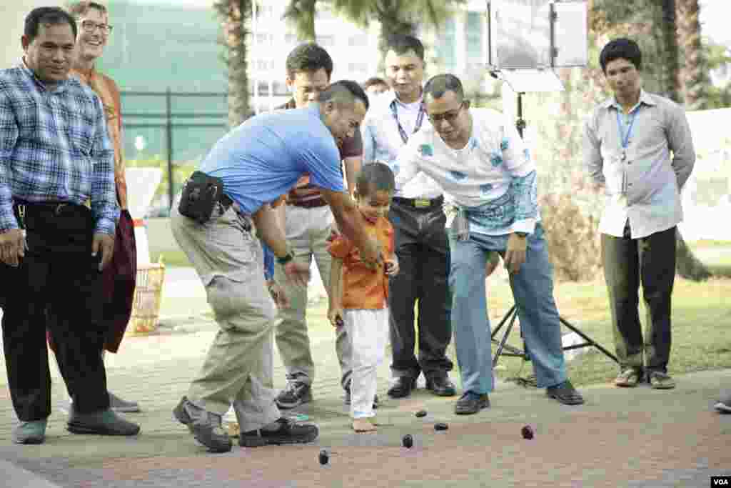 មន្រ្តី​ស្ថានទូតអាមេរិកប្រចាំកម្ពុជាកំពុង​​​លេងល្បែង​ប្រជាប្រិយ​បោះអង្គញ់​ ក្នុង​ការ​ប្រារព្ធ​ពិធី​បុណ្យ​​ចូល​ឆ្នាំ​ថ្មី​​ប្រពៃណី​ជាតិ​ខ្មែរ នៅ​ក្នុង​បរិវេណ​​​ស្ថានទូត​​អាមេរិក​​ប្រចាំ​​កម្ពុជា​ នា​ថ្ងៃទី​៦ ខែមេសា ឆ្នាំ​២០១៨។(ទុំ ម្លិះ/VOA)