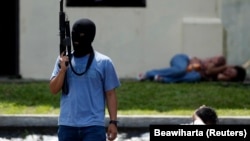 Seorang teroris tiruan memegang senapan di dekat "warga sipil yang ditahan" dalam latihan anti-teror di markas pasukan khusus polisi di Depok, Jawa Barat, 9 Maret 2010. (Foto: REUTERS/Beawiharta)
